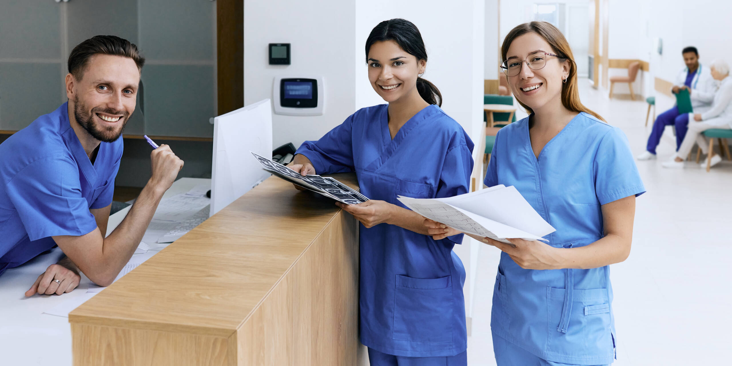 Nurse on duty talking with medical assistants during working day in medical clinic standing near reception desk at hospital lobby. Medical staff of clinic